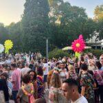 Großes Sommerfest mit vielen Teilnehmenden im Außenbereich. Bunte, aufblasbare Blumen dienen als dekorative Elemente. Die Stimmung ist gesellig und sommerlich.